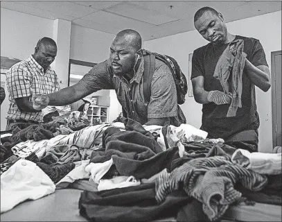  ?? [AARON VINCENT ELKAIM/THE NEW YORK TIMES] ?? Seidu Mohammed, right, and Razak Iyal, beside him, volunteer at the Canadian Muslim Women’s Institute in Winnipeg, Manitoba. The two Ghanaian refugees became the public faces of desperatio­n among refugees in the United States after Donald Trump’s...