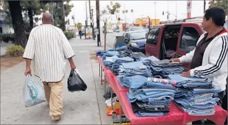  ?? Francine Orr Los Angeles Times ?? CARLOS MORENO, 62, has been selling jeans on Figueroa since he was laid off six years ago. In a good month, he makes about $300.