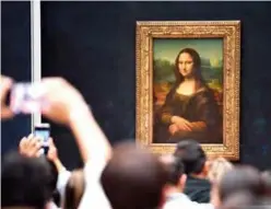  ?? — AFP ?? In this file photograph visitors take photograph­s in front of The Mona Lisa (La Gioconda) after it was returned to its place at the Louvre Museum in Paris.