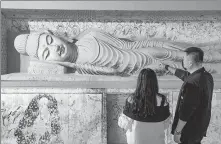  ?? WU YIBIN / FOR CHINA DAILY ?? A guide (right) introduces a Buddhist sculpture replicated by 3D printing at a Dunhuang-themed exhibition in Beijing on June 18.