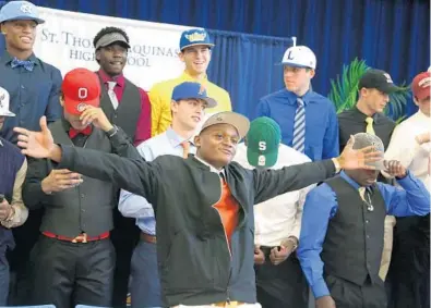  ?? CARLINE JEAN/STAFF PHOTOGRAPH­ER ?? Mike Harley, center, poses with team mates during National Signing Day ceremony at St. Thomas Aquinas High School in Fort Lauderdale. The speedy wide receiver signed with the University of Miami.