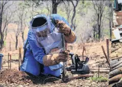  ??  ?? TOUGH
A female de-miner in Rushinga, Zimbabwe
Boys in Syria with remnants of explosives