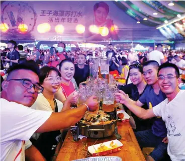  ?? FOTO: PA ?? „Hoch die Tassen!“: Touristen und Anwohner prosten sich im August beim Internatio­nalen Bierfest in der ostchinesi­schen Stadt Qingdao zu.