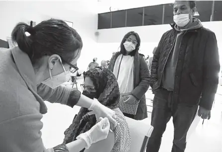  ?? Kathryn Scott, Special to The Denver Post ?? Irine Hoque receives her second Moderna COVID-19 vaccine from Ivana Loos, left, a registered nurse from the Colorado Primary Care Clinic, while Hoque’s husband Syed, right, and daughter Naveen, 12, watch Sunday during a vaccine equity clinic hosted at the Colorado Muslim Society.