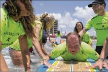  ??  ?? Sylvester Barry of Austin gets on a surfboard at the event, which was hosted by the Life Rolls On nonprofit, with the help of volunteers.