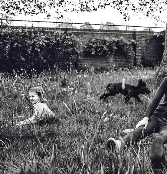  ??  ?? Family life: William relaxes in the Kensington Palace garden with Kate, who is laughing as she watches three-year-old George, a smiling Charlotte and Lupo the spaniel