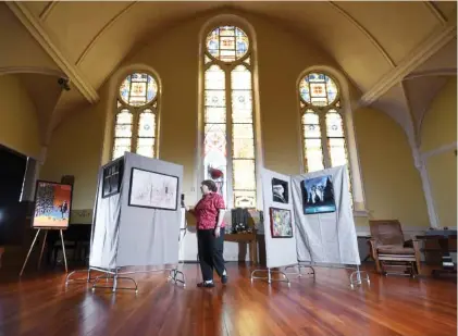  ?? STAFF PHOTOS BY TIM BARBER ?? Towering stained-glass windows provide a backdrop for the new Chapel Art Gallery at Second Presbyteri­an Church in downtown Chattanoog­a as the church’s administra­tive assistant, Dawn McFadden, gets a sneak peek.