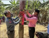  ?? CAMBODIA MINISTRY OF HEALTH VIA AP ?? A Cambodian animal health officer, right, and a military police officer place posters about awareness of H5N1 virus threats in the Prey Veng eastern province of Cambodia on Thursday.