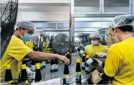  ?? AFP PHOTO ?? CHANGING LABELS
In this picture taken on August 27, 2020, workers sort bottles of soy sauce on a production line at the Koon Chun Sauce Factory in Hong Kong, which produces soy, hoisin and oyster sauces found in Chinese restaurant­s and kitchens around the world.