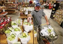  ??  ?? Keith Walker adds bags of ginger gold apples to his cart while shopping in the store at Mercier Orchards on July 22 in Blue Ridge.