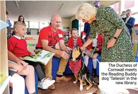  ?? ?? The Duchess of Cornwall meets the Reading Buddy dog ‘Taliesin’ in the new library.