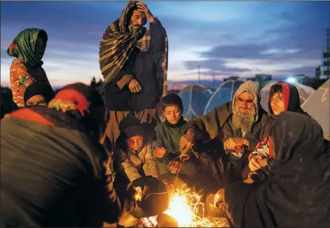  ?? (AP/Petros Giannakour­is) ?? A family warms up next to makeshift fire Nov. 29 outside the Directorat­e of Disaster office where they are camped in Herat, Afghanista­n. About 2,000 internally displaced people left Allahyar village in Ghor province because of a drought and are seeking help from the regional government in Herat.