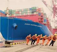  ??  ?? Porto di Qingdao.
Al lavoro con la maschera anti-virus
REUTERS