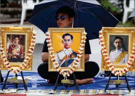  ??  ?? A Thai woman sits behind portraits of the late Thai King Bhumibol Adulyadej, as she waits to take part in the Royal Cremation ceremony, in Bangkok, Thailand on Tuesday.