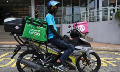  ?? Photograph: Mohd Rasfan/AFP/Getty Images ?? A Grab delivery rider making deliveries in Kuala Lumpur, Malaysia.