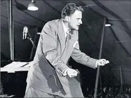  ?? HULTON ARCHIVE ?? The Rev. Billy Graham preaches during a tent revival in the mid-1950s. Graham became famous beginning in the late 1940s thanks to his energetic and folksy style of preaching.
