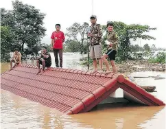  ?? ATTAPEU TODAY VIA THE ASSOCIATED PRESS ?? Villagers take refuge on a rooftop above flood waters from a collapsed dam that left hundreds missing in the Attapeu district of southeaste­rn Laos on Tuesday.