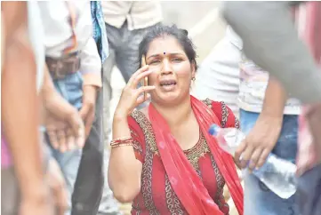  ??  ?? Ranjan Dhimali, wife of Indian constructi­on worker Ranjeet Dhimali who was thought to be in an under constructi­on building that collapsed, talks on the phone near the site of the in the village of Shah Beri village in Greater Noida. — AFP photos