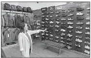  ?? AP/TERRY CHEA ?? Jennifer Lee, whose family owns Footprint shoe store in San Francisco, points to a wall of athletic shoes, many of which are made in China and will be subject to new U.S. tariffs on Chinese goods starting today.