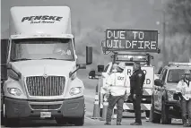  ?? David Zalubowski, The Associated Press ?? A deputy with the Boulder County Sheriff ’ s Office stops a truck driver along U. S. 36 at a roadblock north of Boulder as wildfires burn throughout the state.