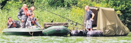  ?? — AFP photos ?? Environmen­tal police officers of the French Biodiversi­ty Office (OFB - Office Français de la Biodiversi­te) talk to an angler during a control operation on Madine Lake in Nonsard-Lamarche, eastern France.