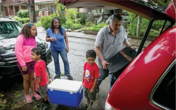  ?? TIM FRASER FOR THE TORONTO STAR ?? Samantha Kemp-Jackson, back left, and her husband, Rick Kogucki, pack up the car for a road trip with their twin boys, Erik, left, and Aubrey, and daughter Miranda outside their Toronto home.