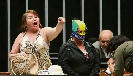  ??  ?? Loud and clear: A woman shouting slogans against graft as a group of people calling for a military coup walk onto the floor of the Chamber of Deputies. — AP