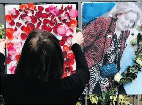  ?? LIONEL BONAVENTUR­E / AFP / GETTY IMAGES ?? A woman places a picture and tributes to Mireille Knoll on the fence surroundin­g her building in Paris Tuesday. Knoll was found dead in her apartment Friday in a stabbing that is being treated as an anti-Semitic hate crime.