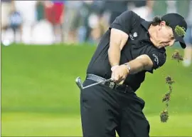  ?? Mike Groll Associated Press ?? PHIL MICKELSON, taking a divot from the fairway on the 12th hole, got within three strokes of Rory McIlroy with an eagle on the last hole.