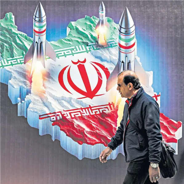  ?? ?? A man walks past a banner depicting missiles launching from a map of Iran in central Tehran yesterday