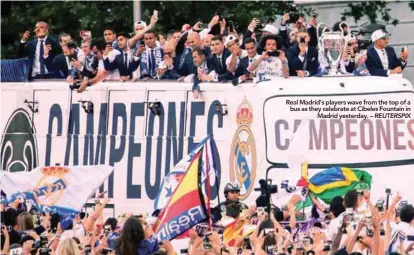  ??  ?? Real Madrid’s players wave from the top of a bus as they celebrate at Cibeles Fountain in Madrid yesterday. – REUTERSPIX