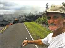  ?? MARCO GARCIA/ASSOCIATED PRESS ?? Resident Sam Knox, 65, rides his bicycle to the edge of the road as lava burns across it Saturday in the Leilani Estates in Pahoa, Hawaii. The Big Island is preparing for weeks or months of upheaval as the Kilauea eruption continues.