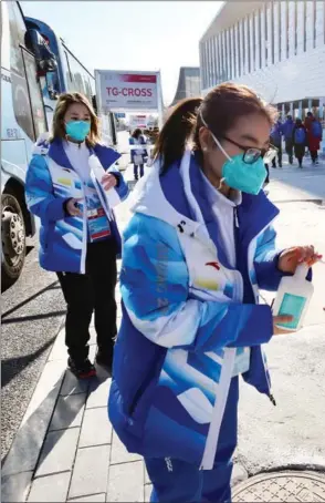  ?? ?? Volunteers sanitize reporters’ hands at the media center during the Beijing Winter Games.