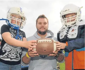  ??  ?? Dundee Hurricanes member Conar Taylor introduces Brogan Taylor, 7, left, and Harry McMaster, 5, to the world of American football.