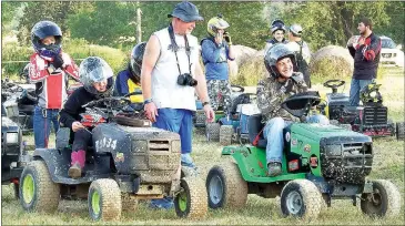  ??  ?? Ray Sandecki helped line up Devin Payne, right, and Maggie Roper, left, as they prepare to race in the Pure Stock division Saturday, July 23, at the Pea Ridge Lions Club’s sixth annual Race for Sight Lawnmower Races at the Patterson farm, Lee Town...