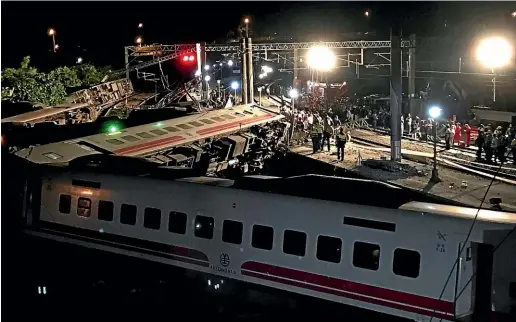  ?? AP ?? Rescue workers gather at the site of a train derailment in Lian county in northern Taiwan.