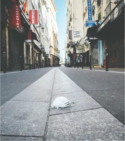  ?? Cyril Marcilhac y / Bloomberg ?? A discarded face mask sits outside shuttered businesses in the Saint Michel district of Paris. The coronaviru­s pandemic has caused hardships for families all over the world, Megan Mcardle writes.