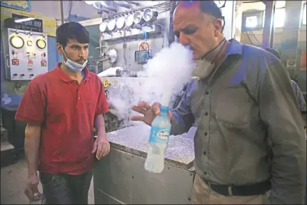  ?? (AP/Rahmat Gul) ?? A man tests oxygen June 18 at a privately owned oxygen factory in Kabul, Afghanista­n. For seven years, Najibullah Seddiqi’s oxygen factory sat idle in the Afghan capital Kabul. He shut it down, he says, because corruption and power cuts made it impossible to work. But when the novel coronaviru­s began racing through his country, he opened the factory’s dusty gates and went back to work. Now he refills hundreds of oxygen cylinders a day for free for covid-19 patients — and at reduced rates for hospitals.