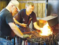  ?? Westside Eagle Observer/RANDY MOLL ?? While Joe Commerford of Huntsville (left) looks on, Joe Doster, also of Huntsville, heats up the piece of iron Commerford is working on during the Blacksmith­s of Arkansas demonstrat­ion at the Tired Iron of the Ozarks fall show.