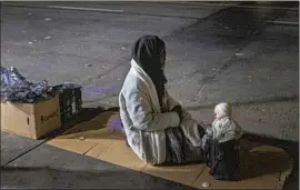  ?? Francine Orr Los Angeles Times ?? A WOMAN sits beside a doll on skid row Thursday. Judge David O. Carter faulted officials’ pursuit of permanent housing at the expense of immediate shelter.