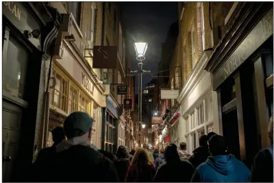  ?? (The New York Times/Gabriella Demczuk) ?? A Jack the Ripper tour moves down an alleyway Whitechape­l, England, east London on Sept. 22. Some alleyways such as this one look much as they might have in the 19th century.