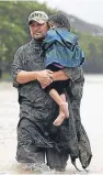  ??  ?? A father walks with his child down a flooded street in Houston.