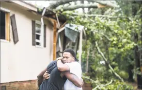  ?? Sean Rayford / Getty Images ?? Hector Benthall, right, gets a hug from his neighbor Keito Jordan after remnants of Hurricane Michael sent a tree crashing into Benthall’s home on Thursday in Columbia, S.C.