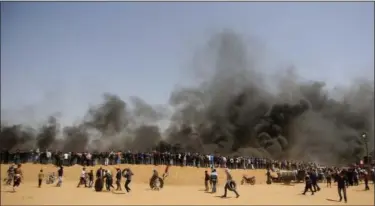  ?? ADEL HANA — THE ASSOCIATED PRESS ?? Palestinia­n protesters stand on sands hill as others carry tires to burn during clashes with Israeli troops along Gaza’s border with Israel, east of Khan Younis, Gaza Strip, Friday. Palestinia­ns torched piles of tires near Gaza’s border with Israel on...