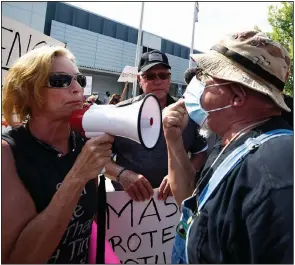  ?? (AP/Mike Stewart) ?? An anti-mask demonstrat­or (left) argues with a pro-mask demonstrat­or Thursday outside the Cobb County, Ga., school board headquarte­rs in Marietta during a rally in support of masks in schools. More photos at arkansason­line.com/813covid19/.