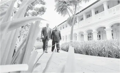  ?? — Gambar Reuters ?? RETORIK: Gambar fail 12 Jun lalu menunjukka­n Trump dan Kim berjalan beriringan sebelum mesyuarat makan tengah hari bersama di Hotel Capella, Pulau Sentosa, Singapura.