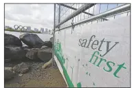  ?? (AP/Eugene Hoshiko) ?? A constructi­on fence featuring the words “Safety First” with a backdrop of the Olympic rings floating in the water in the Odaiba section in Tokyo. .