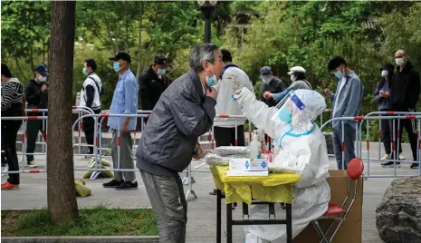  ?? AFP ?? A health worker takes a swab sample from a man in Beijing. Tough Covid-19 restrictio­ns are in place in the Chinese capital