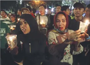  ?? AP PHOTO ?? Women hold candles during a vigil for the victims of the church attacks in Surabaya, East Java, Indonesia.
