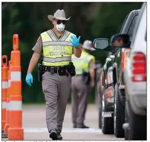  ?? (AP/David J. Phillip) ?? A Texas Department of Public Safety trooper directs traffic Monday at a checkpoint in Orange. The troopers are checking motorists crossing the border from Louisiana to determine whether they need to self-quarantine after their arrival. More photos at arkansason­line.com/47outbreak/.